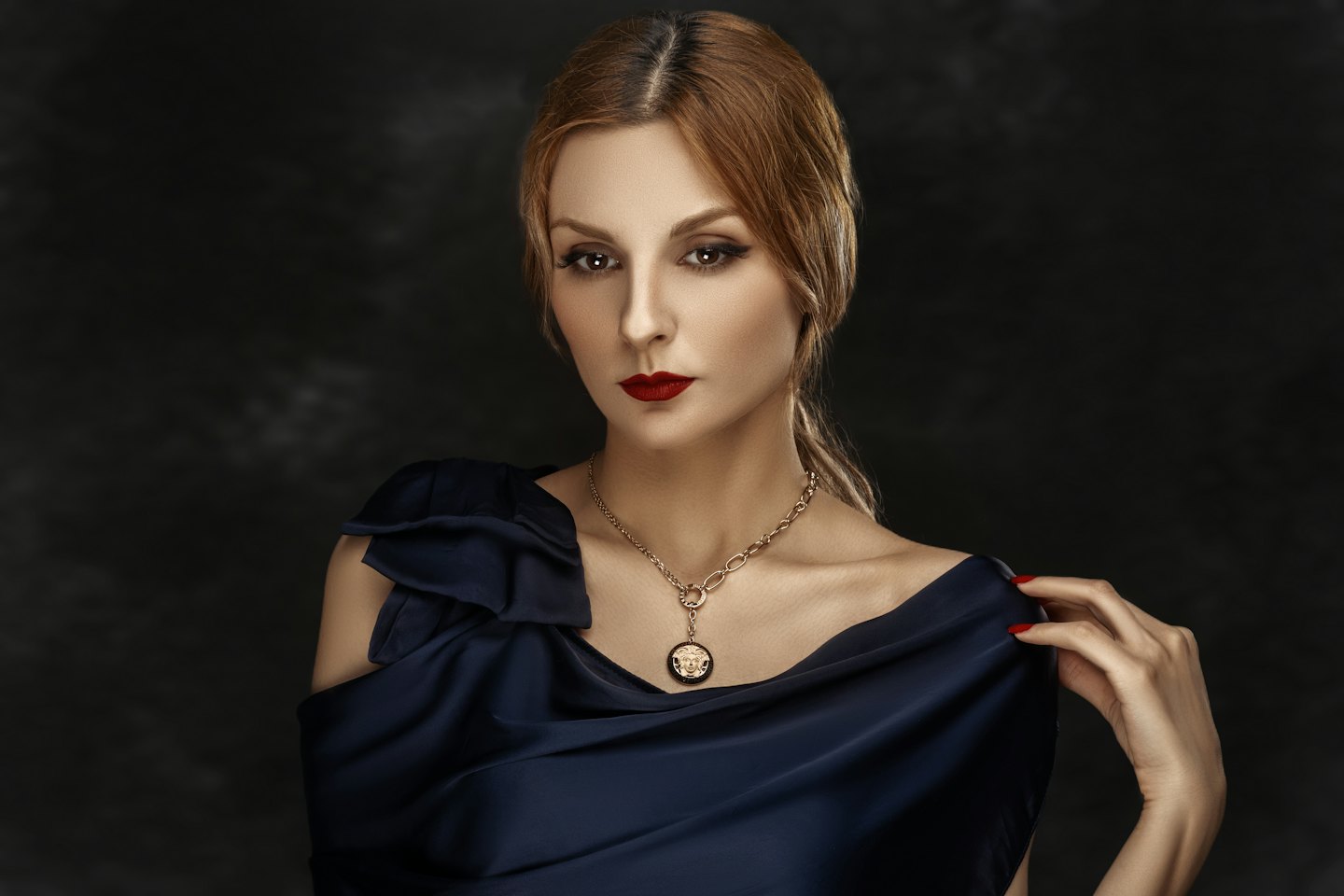 Donna in abito blu navy si tocca la spalla.