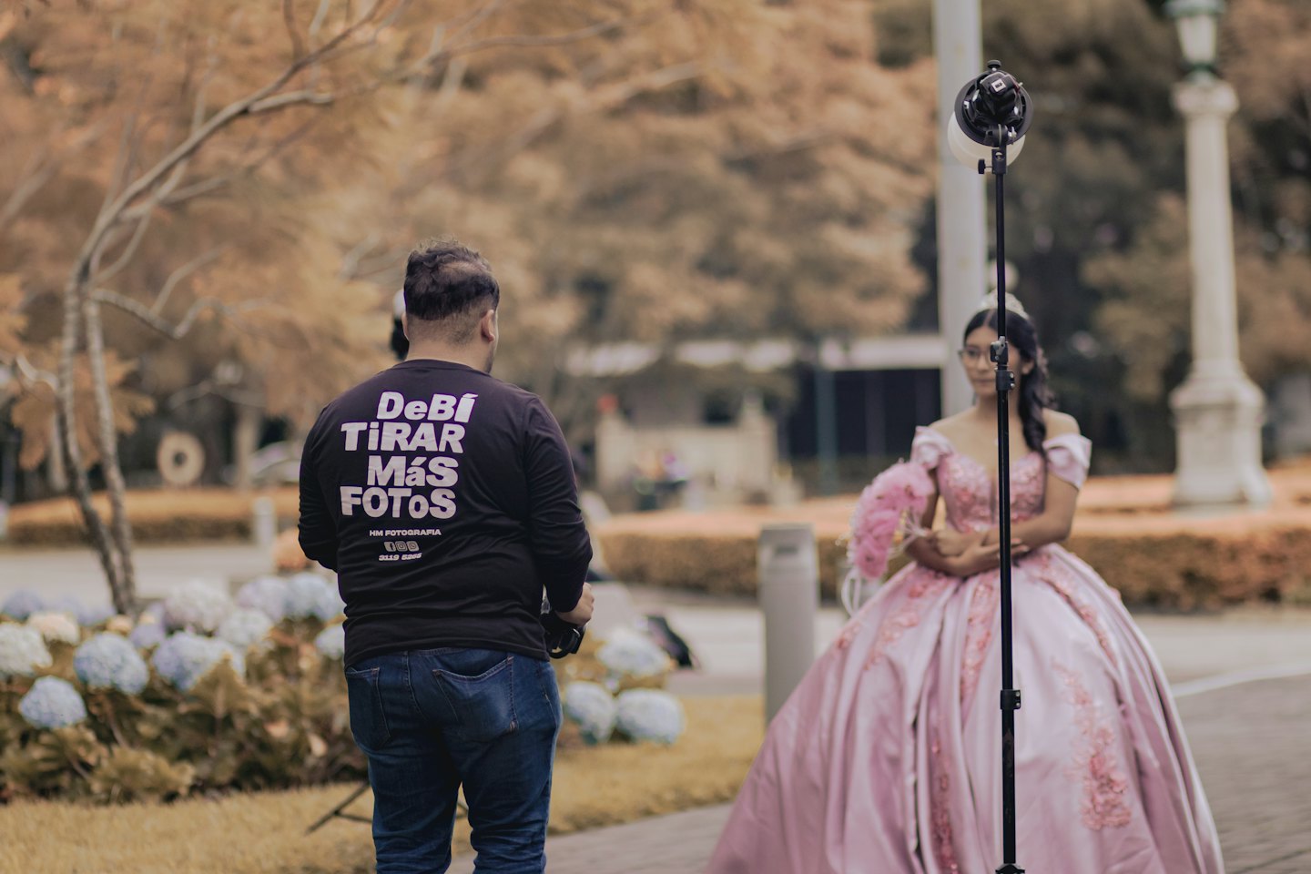 Una fotografa dirige una donna con un abito rosa e un ventaglio di piume.