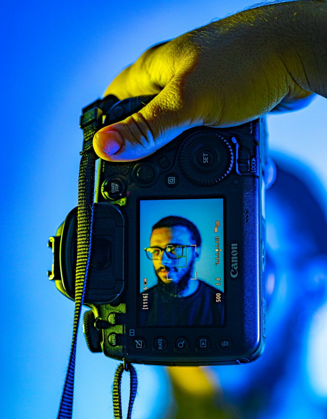 Mano che tiene una fotocamera digitale con il ritratto di un uomo barbuto.